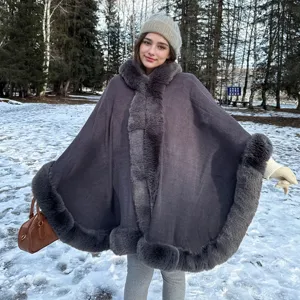 Poncho en tricot chaud avec capuche et bordure en fausse fourrure dans une forêt enneigée