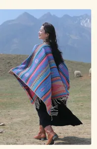Boho-Strickponcho im Ethno-Stil mit Quasten in einer malerischen Gebirgslandschaft