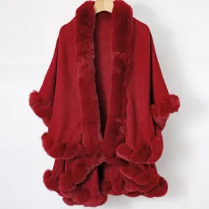 Close-up detail of a luxury red knitted shawl with elegant faux fur trim and pom-pom hemline