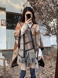 Asiatisches Model in einem Retro-Karo-Poncho-Schal mit Fransen in herbstlicher Umgebung