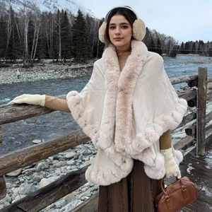 Beige knitted shawl with faux fur trim worn by a model in a winter outdoor setting