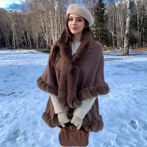 Elegant brown knit cape shawl with plush fur collar and hem shown in a snowy forest scene