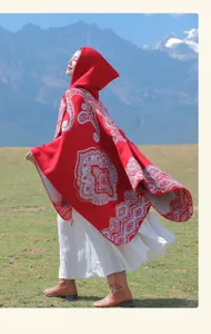 Roter Kapuzen-Poncho im Ethno-Stil mit Mustern vor malerischer Bergkulisse im Freien