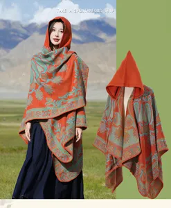 Detail des ethnischen Paisley-Musters und der Kapuze am orangefarbenen Strick-Reiseschal.
