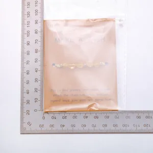 Detail eines handgefertigten Naturstein-Armbands mit Wunschkarte und Metalllineal.