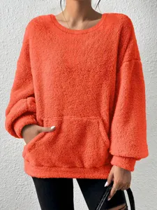 Close-up of fluffy orange sweatshirt detail, showing soft fleece texture and front pocket design.