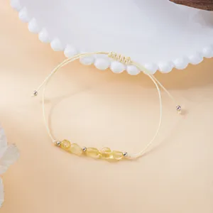 Detailaufnahme eines handgewebten Armbands mit unregelmäßigen gelben Natursteinen