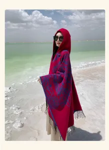 Close-up of ethnic hooded shawl in red with blue patterns and fringe for outdoor travel