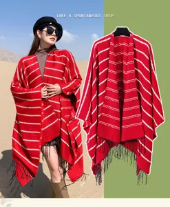 Red ethnic striped knitted poncho shawl with black tassels worn by model in desert