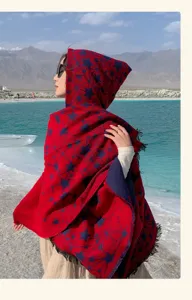 Red and navy star pattern hooded knitted shawl worn by a model in a scenic landscape
