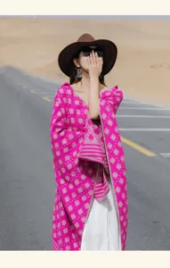 Bohemian ethnic style magenta pink knitted shawl poncho worn on a scenic road for travel