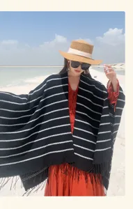 Stylish black and white striped knitted shawl with tassels worn by model at the beach