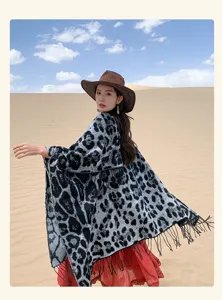 Leopard print fringed knit poncho shawl worn by a model in a desert setting.