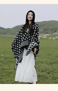 Asian model wearing a retro black and white ethnic knit hooded shawl in a grassy field scene