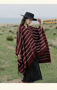 Burgundy ethnic style striped shawl with tassels worn by model in a grassy field