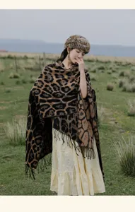 Stylish leopard print fringe knitted shawl poncho worn by a model in a scenic prairie landscape