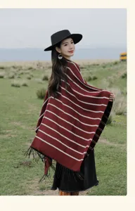 Asian model wearing a thick burgundy striped knitted shawl with tassels in a scenic meadow