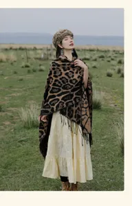 Outdoor lifestyle view of a leopard print knitted shawl with tassels in a grassland