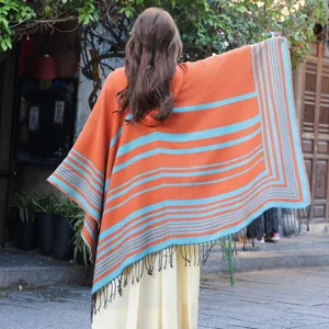 Detailed view of the back of a striped orange and teal knitted shawl with tassels