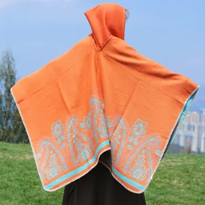 Rückansicht eines orangefarbenen Strickponchos mit Kapuze und blauem Paisley-Muster