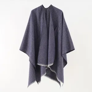 Detailed view of textured knit shawl poncho with fringed edges in navy blue