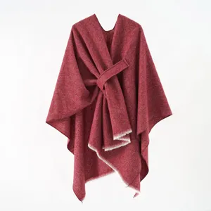 Detailed shot of a red knitted poncho shawl featuring a stylish diagonal strap design