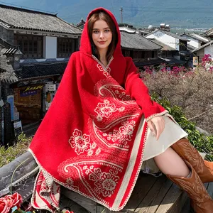 Detailansicht eines roten Strick-Ponchos mit Kapuze und eleganten Paisleymustern.