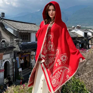 Roter Damen-Strickponcho mit Kapuze und elegantem Blumenmuster vor einer malerischen Kulisse