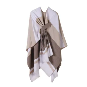 Dettaglio di uno scialle poncho in maglia a righe con nodo laterale e bordi con frange