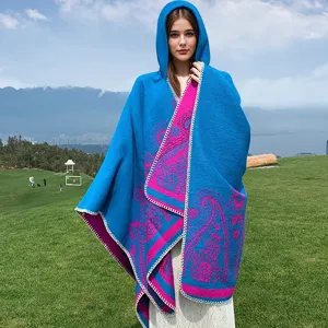 Detailansicht eines blauen Boho-Ponchos mit Kapuze und Paisleymuster in der Natur.