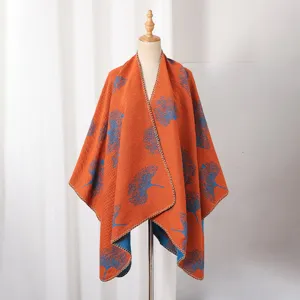 Detailansicht eines herbstlichen Strickponchos mit blauem Ginkgo-Muster auf orangefarbenem Grund