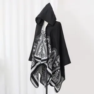 Detailansicht eines schwarzen Kapuzenponchos mit böhmischem Blumenmuster auf einer Puppe.