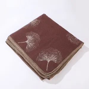 Detailansicht eines gefalteten weinroten Strickschals mit elegantem Ginkgoblatt-Jacquardmuster.