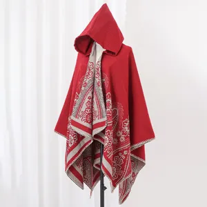 Detail eines roten Strickponchos mit Kapuze, Ethno-Paisley-Muster und Fransenrändern