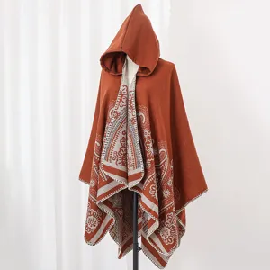 Detailansicht eines rostorangen Kapuzenponchos aus Strick mit ethnischem Blumenmuster