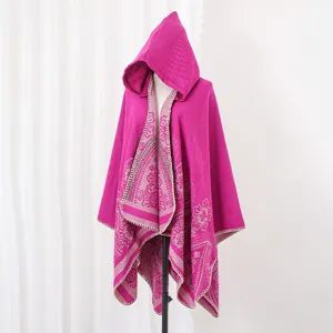 Detailaufnahme eines fuchsiafarbenen Strickponchos mit Kapuze und Blumenmuster.