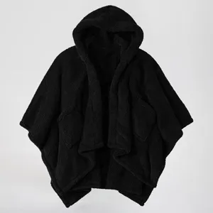 Close-up detail of the black fleece hooded cape showing cozy textured fabric and deep front pockets.