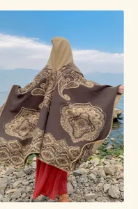 Rückansicht eines ethnischen Kapuzenschals mit Paisleymuster an einem felsigen Ufer