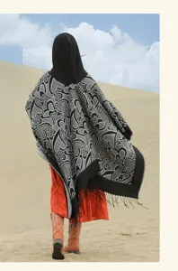 Vue de dos d'un poncho à capuche avec franges et motifs de cœurs dans un décor de désert
