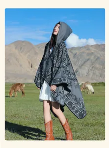 Asiatin in grauem Paisley-Kapuzenponcho vor einer Berglandschaft