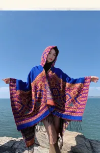 Outdoor view of a vintage hooded poncho with ethnic floral patterns and stylish fringe