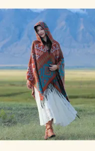 Eleganter böhmischer Strickponcho mit Kapuze und blau-orangen Mustern in der Natur