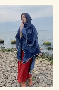 Detailansicht eines ethnischen Kapuzenschals mit blauem Muster vor malerischer Seekulisse