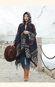 Asiatisches Model im böhmischen Strickponcho mit Kapuze und Fransen vor Schneelandschaft