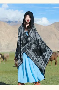 Detailansicht eines gestrickten Kapuzenschals mit Paisleymuster in einer Berglandschaft