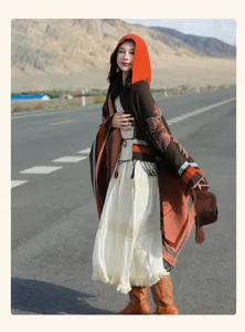 Ethno-Kapuzenponcho für Damen mit Blumenstickerei und Quasten auf einer malerischen Straße.