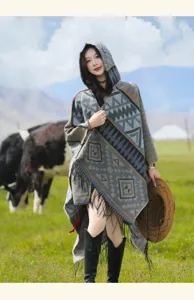 Böhmischer Strickponcho mit Kapuze, geometrischem Muster und Quasten auf grüner Wiese
