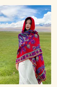 Roter Strickschal mit Kapuze und Paisleymuster für Damen in einer Wiesenlandschaft