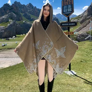 High-quality detail of hooded knit poncho with butterfly patterns in a mountain landscape