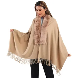 Détail du poncho élégant couleur camel avec col en fausse fourrure et franges pour l'hiver